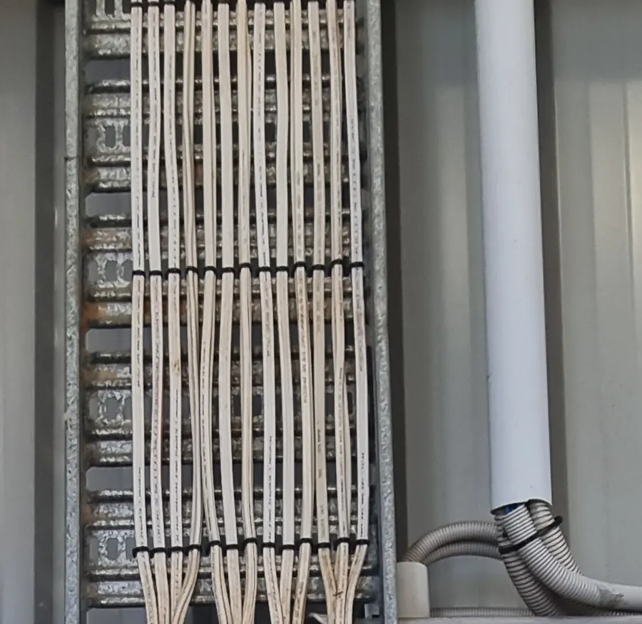 Circuit cabling dressed and cleated in neat parallel runs along a galvanised cable ladder above a distribution board